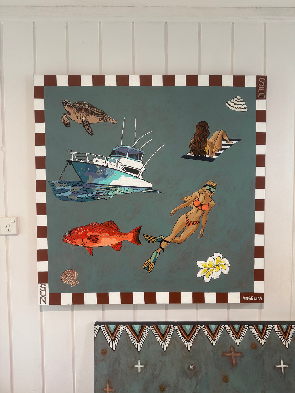 Decorative wall art with beach-themed elements on a white wall.