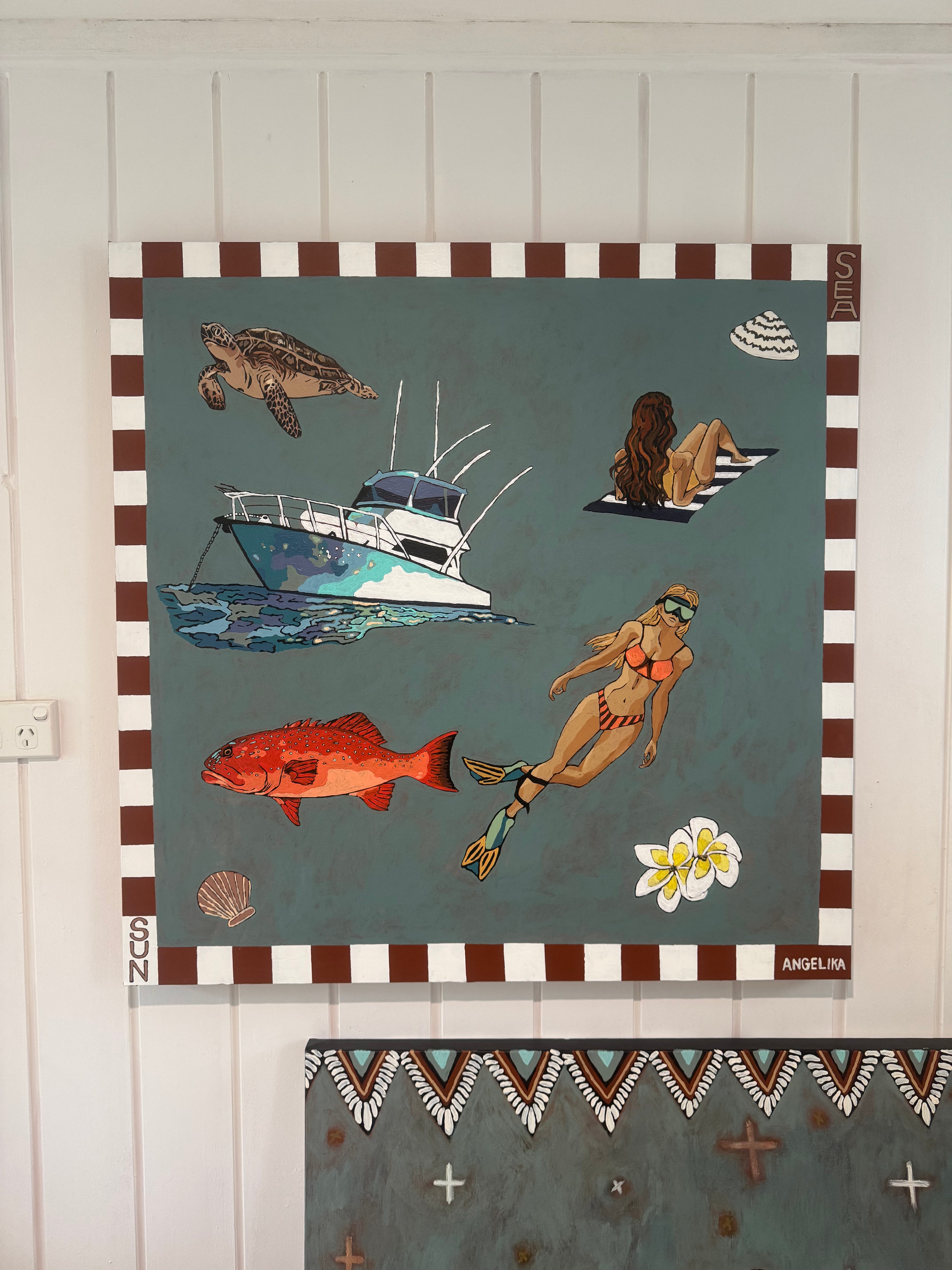 Decorative wall art with beach-themed elements on a white wall.