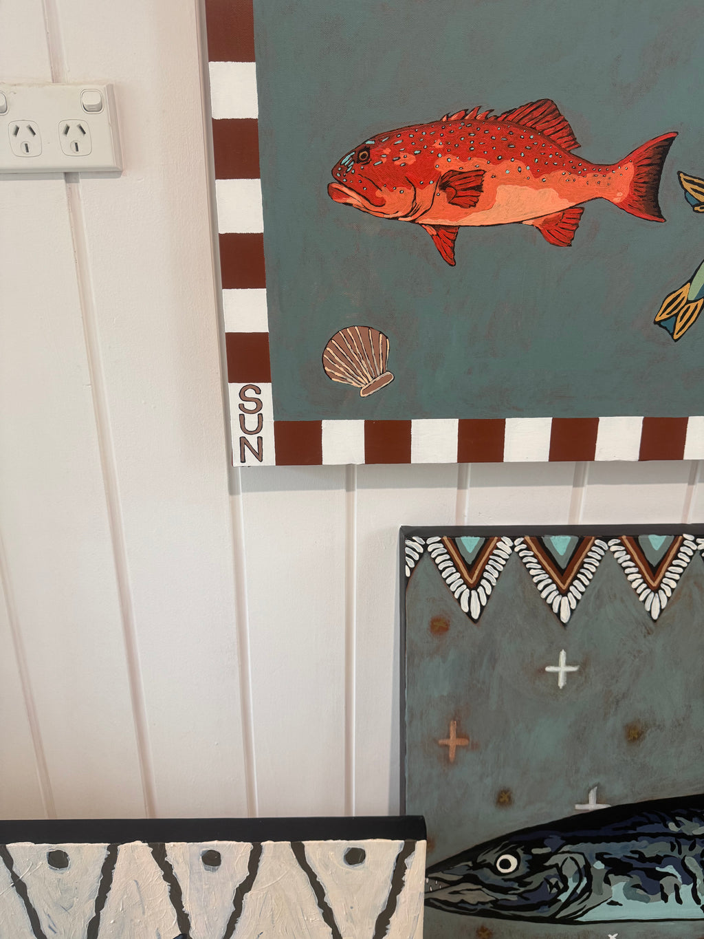 Decorative wall art with a fish design on a striped background.