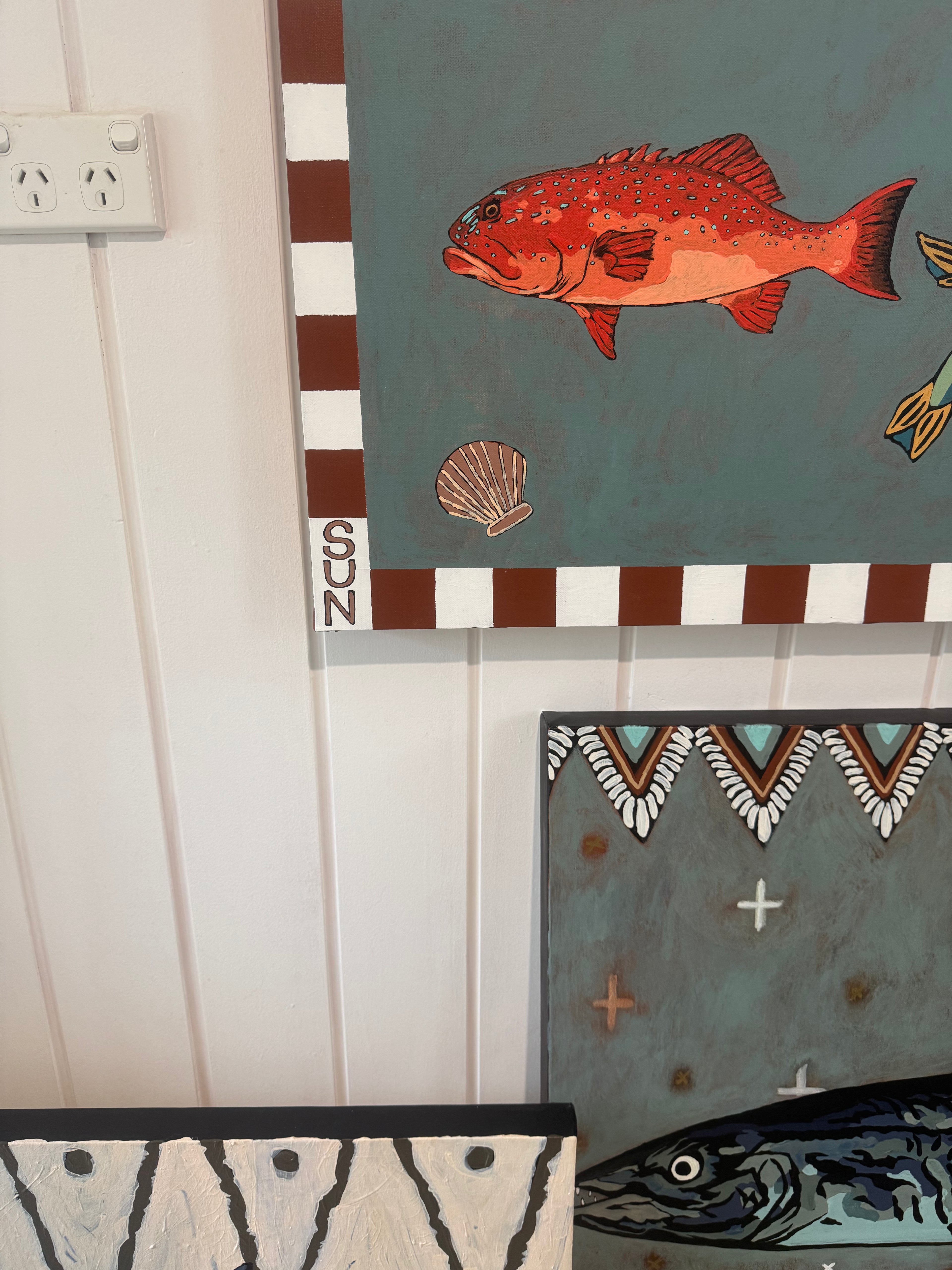 Decorative wall art with a fish design on a striped background.